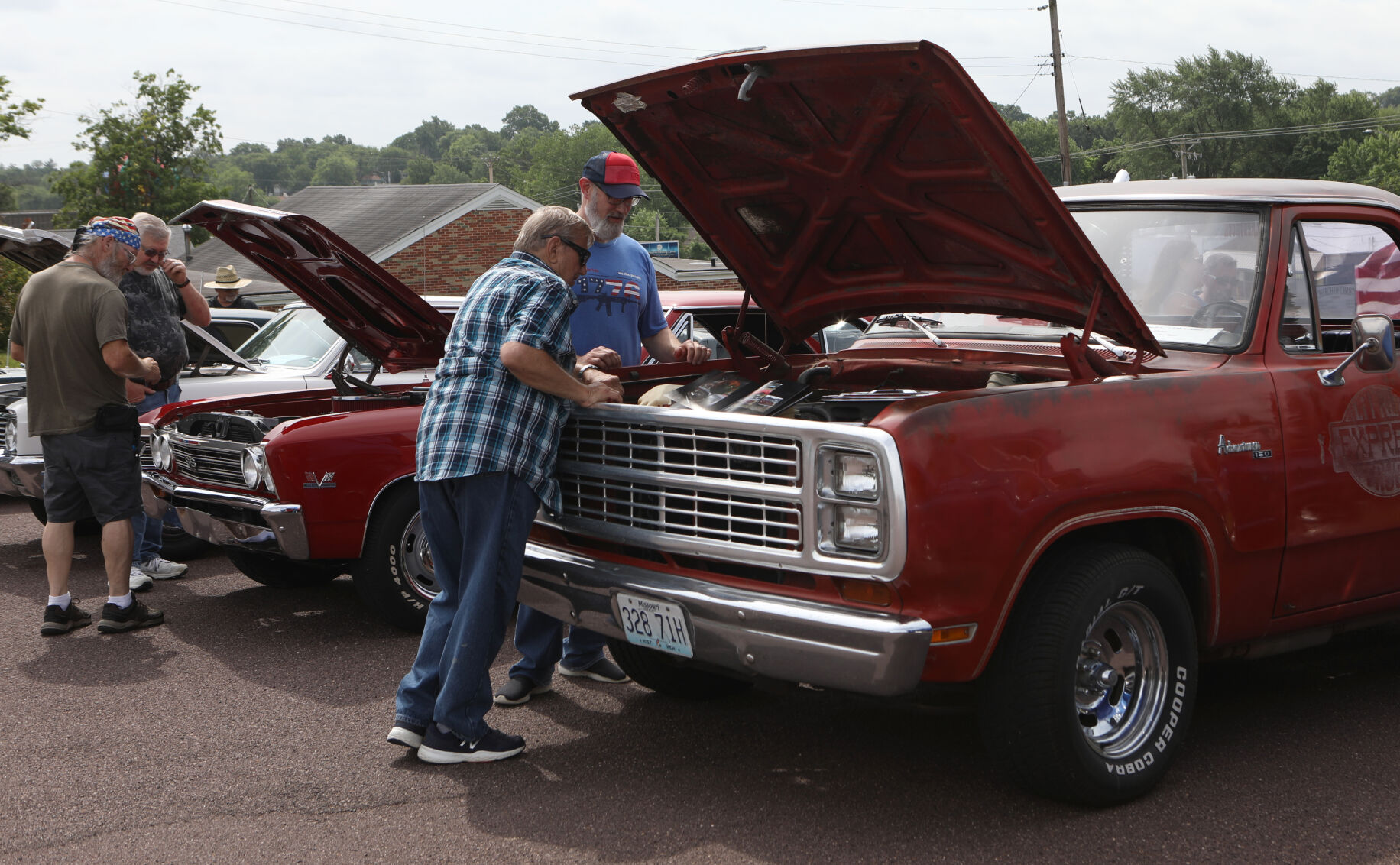 Larry Runnels and Shawn Rhodes look under the hood of a car